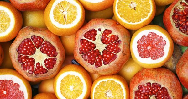 orange et grenades en quantité dont le dessus est coupé pour faire apparaitre la chair